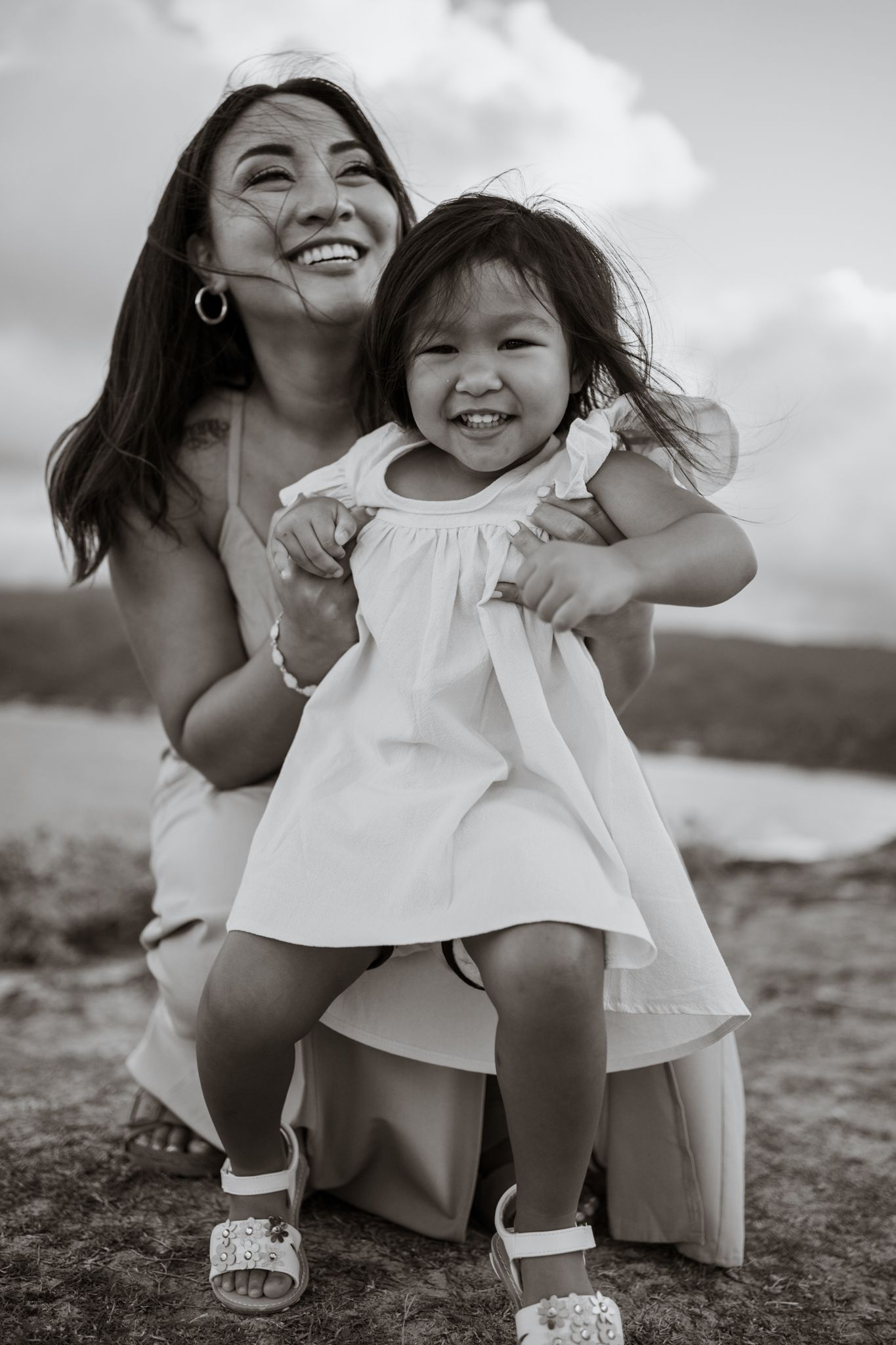 Black and white portrait of parent and child sharing joyful moment outdoors.