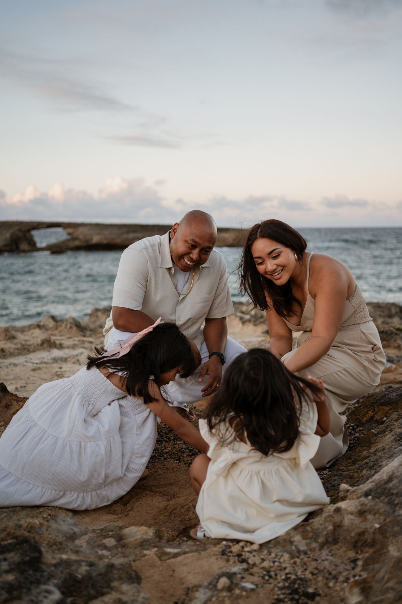 Family gathering on rocky coastal cliffs at sunset sharing intimate moments together.