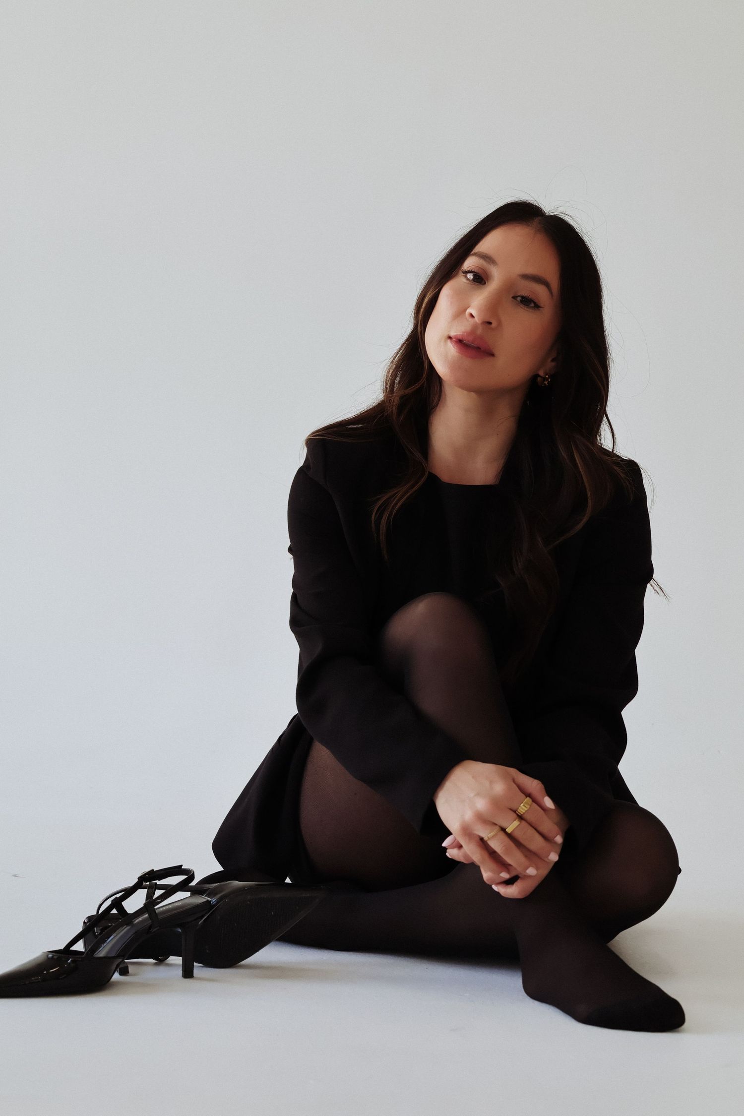 Minimalist fashion portrait featuring all-black ensemble against white background.