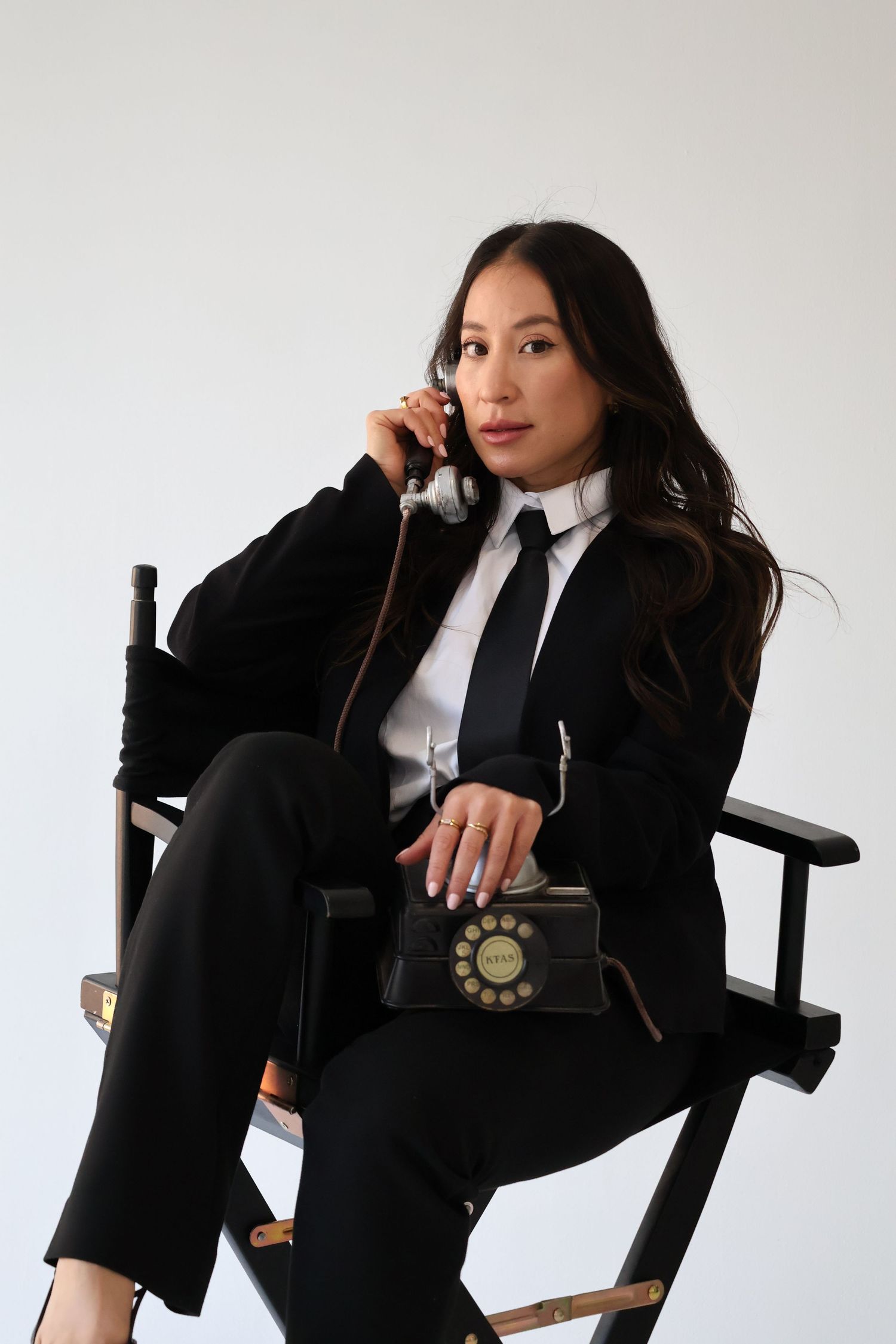 Business portrait in black suit and tie with retro telephone on director's chair.