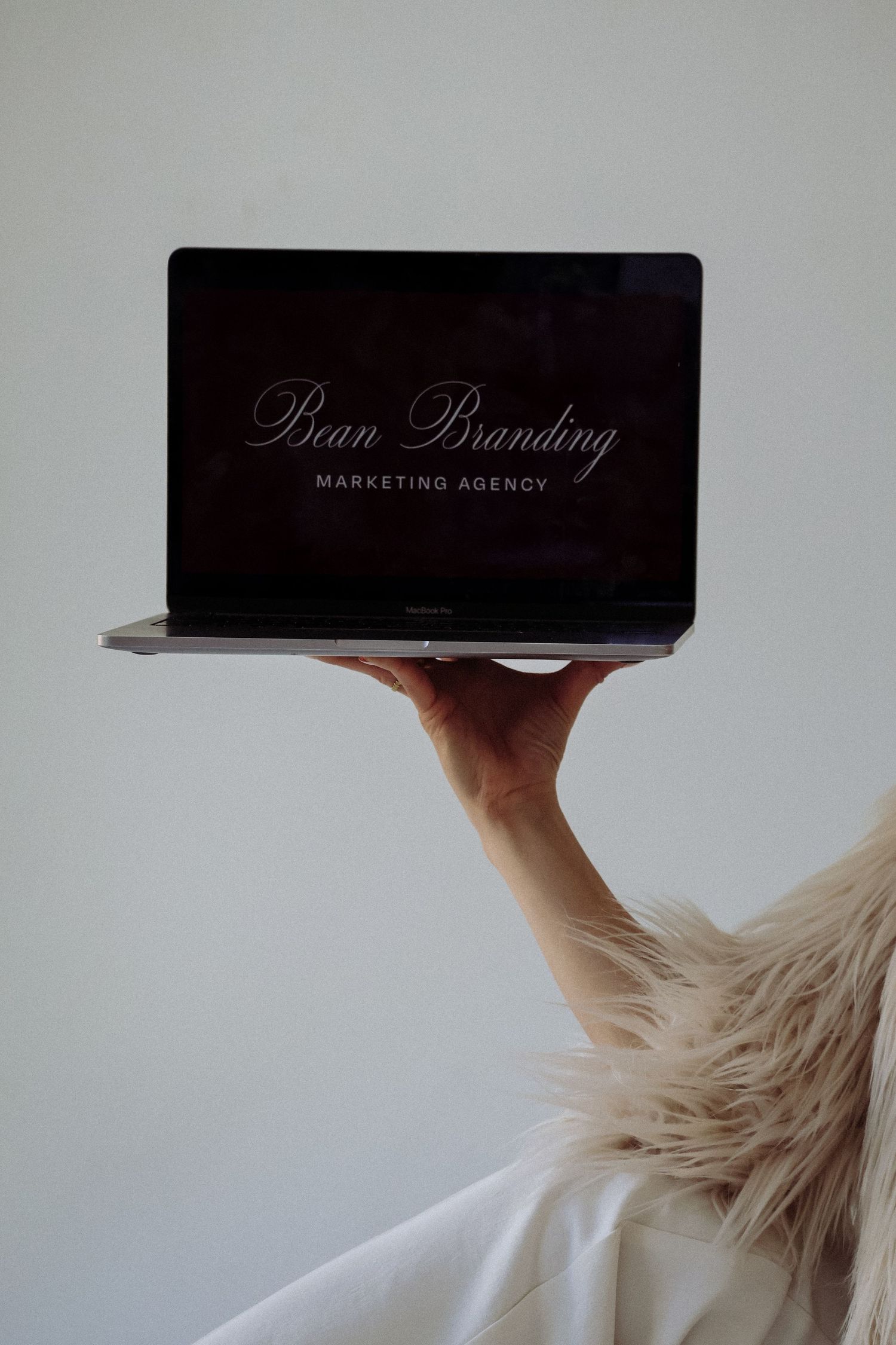 Pure Branding Marketing Agency displayed on laptop screen held up against light background.