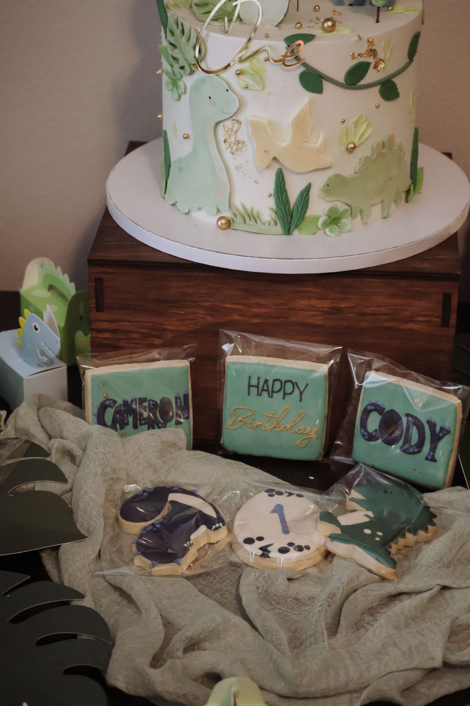 A dinosaur-themed cake and coordinating cookies decorated in green and white.
