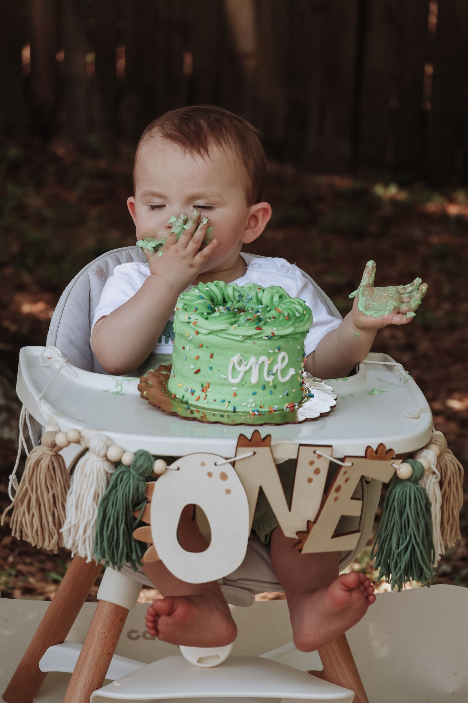 Birthday celebration features messy eating of a green frosted cake with ONE sign.