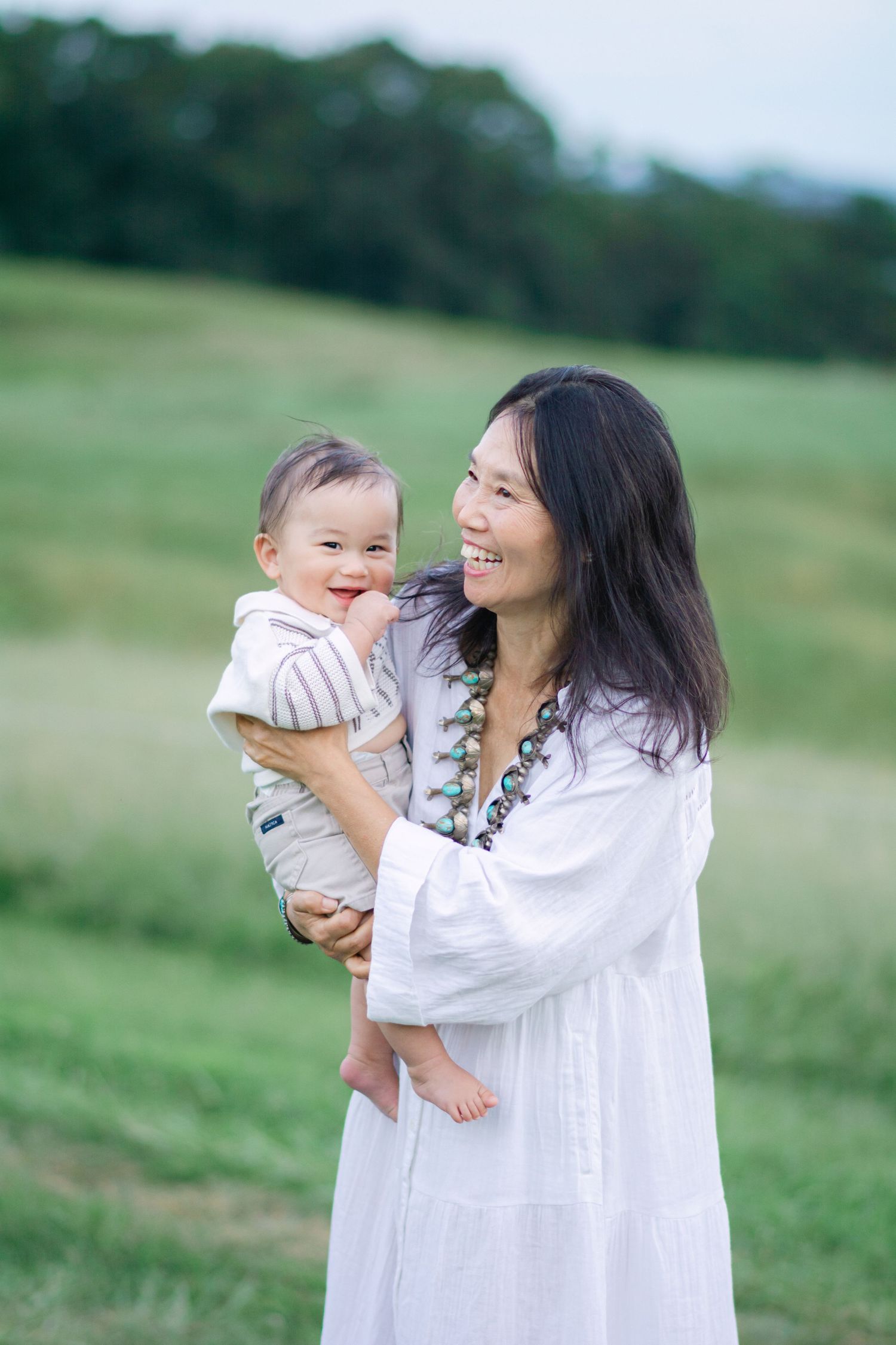 Mother and baby sharing joyful moments together in a green meadow setting.
