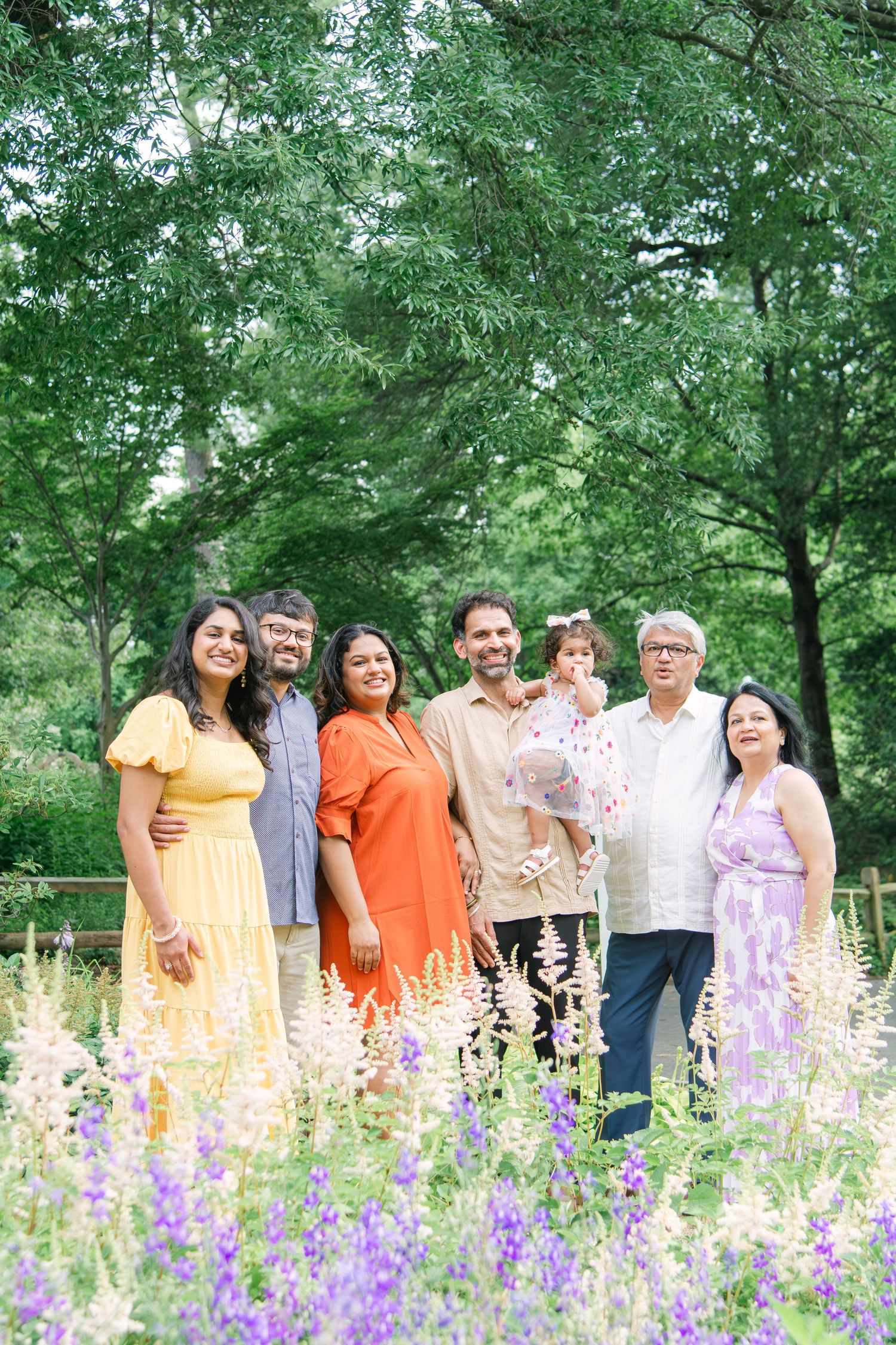 Extended family gathering outdoors with purple wildflowers blooming in the foreground.