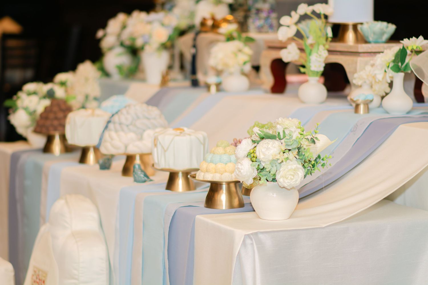 Wedding dessert table decorated with white floral arrangements and blue table linens.