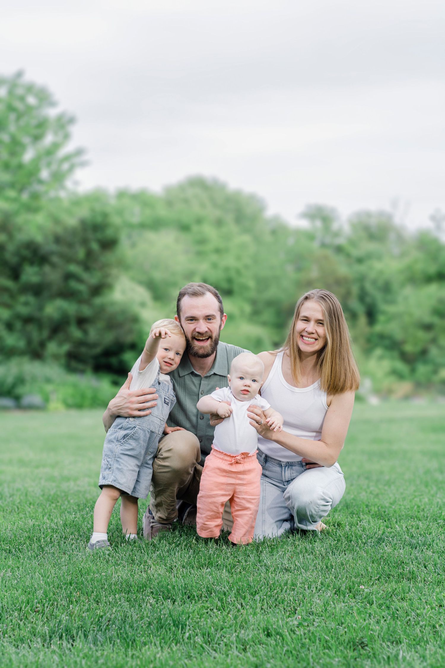Family lounges on green grass during outdoor photo session.
