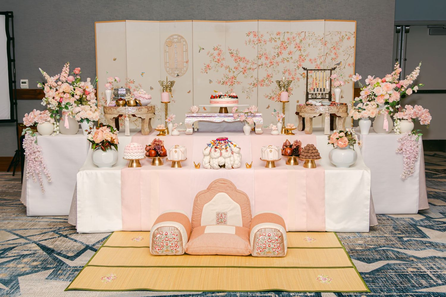 Elegant dessert table setup with pink and white decor and floral arrangements.