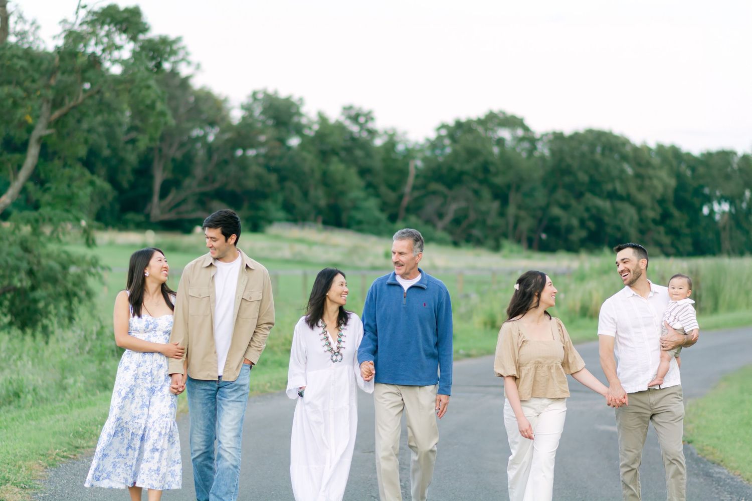 Family in coordinated white and blue outfits walking together outdoors on a sunny day.