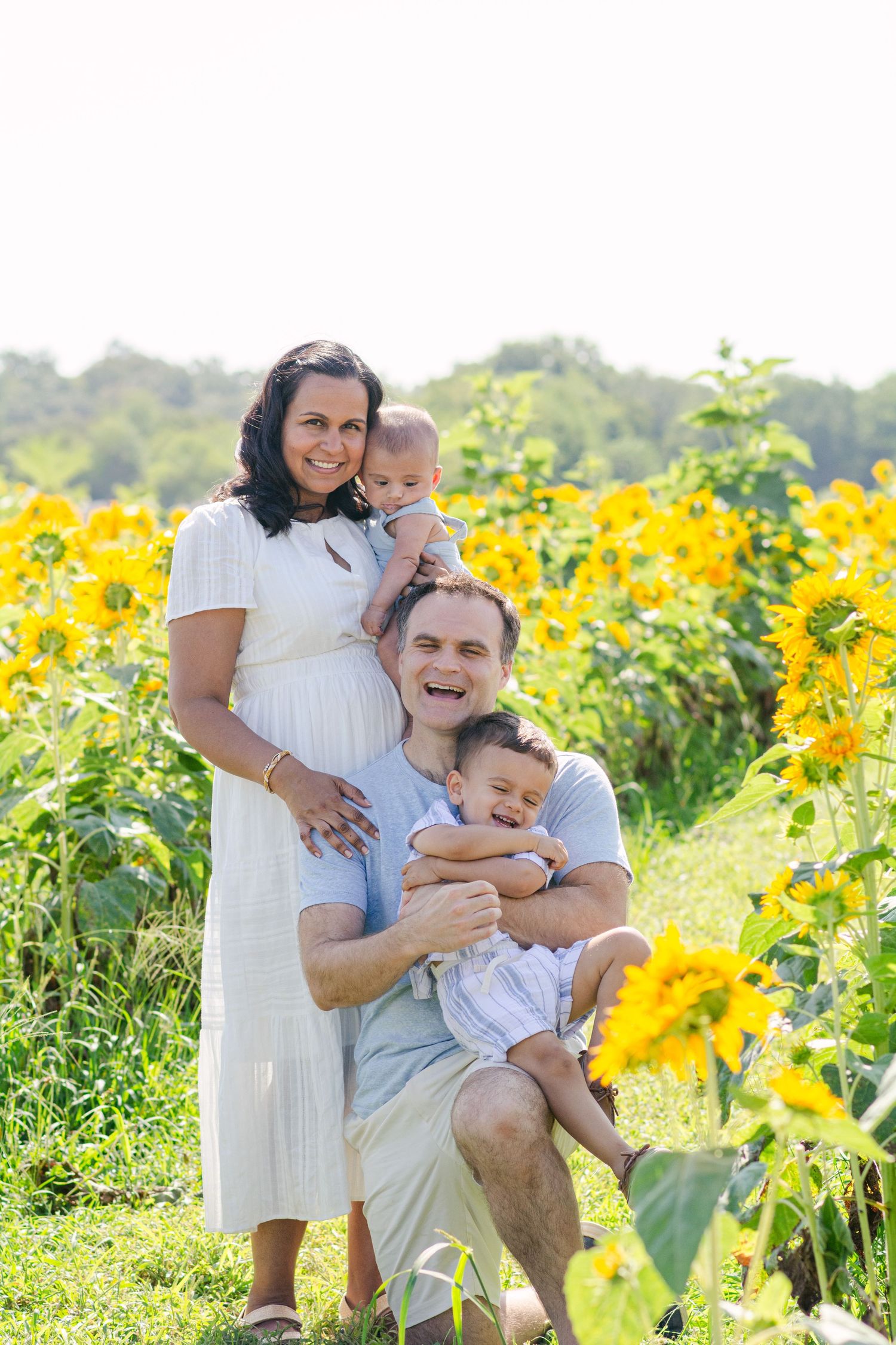 Family shares tender moment together in blooming sunflower field.