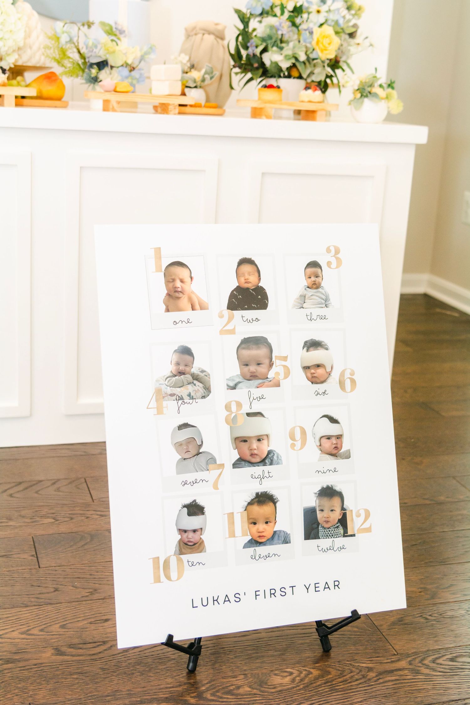 First year milestone photo display boards on wooden floor showing baby's monthly progress.
