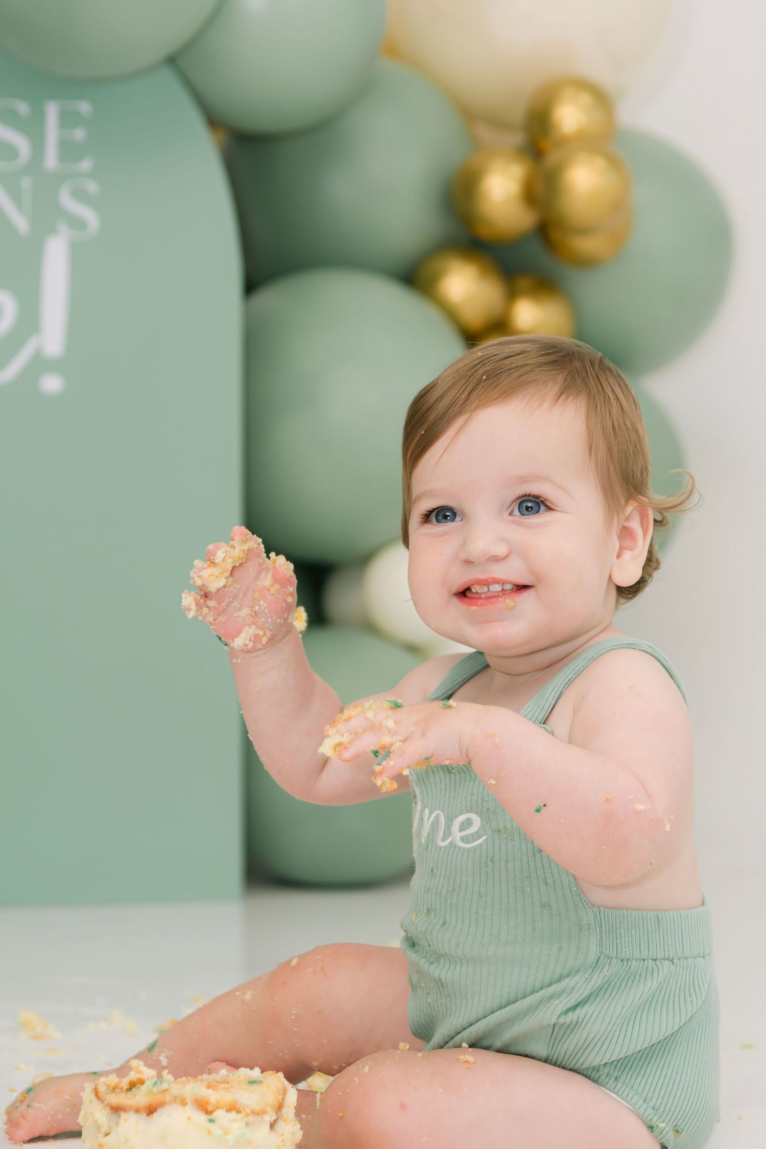 Baby's first birthday cake smash session with mint green and gold decorations.