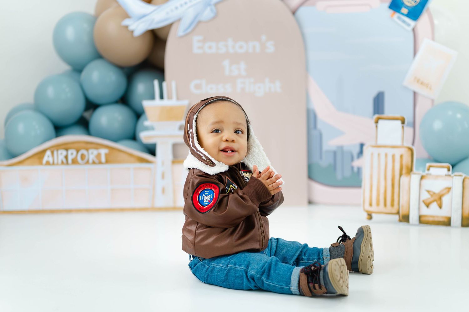 Baby photography session with blue and beige nursery decor featuring airplane theme and balloons.