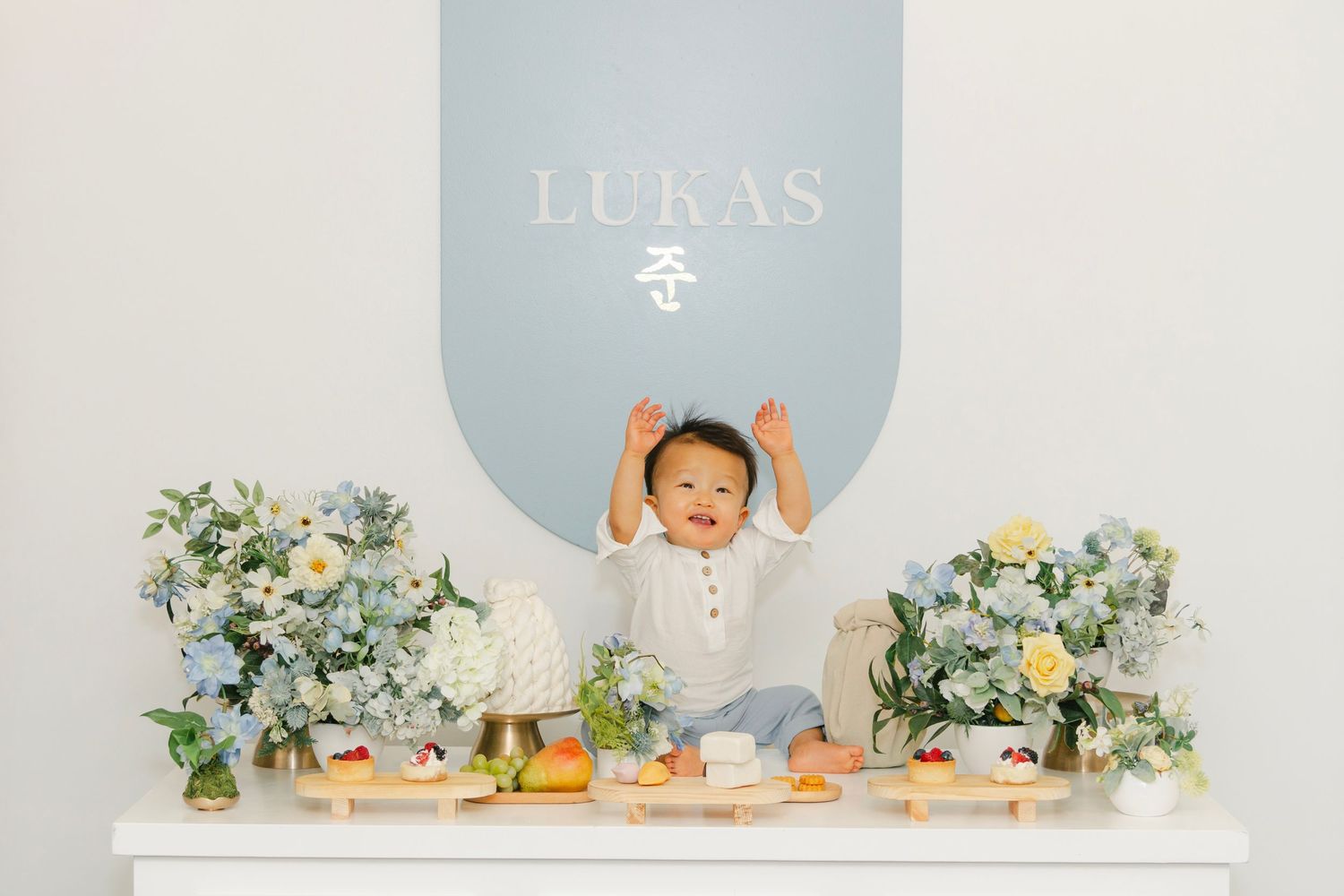 Modern party venue with white furniture, blue accent wall, and name 'LUKAS' displayed.
