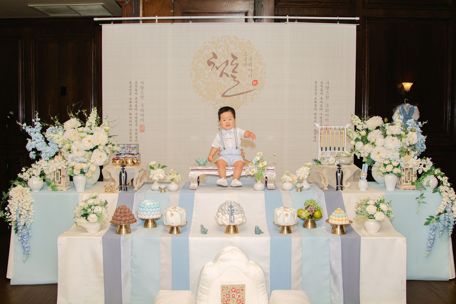 Elegant party setup with blue and white themed decorations and floral arrangements.