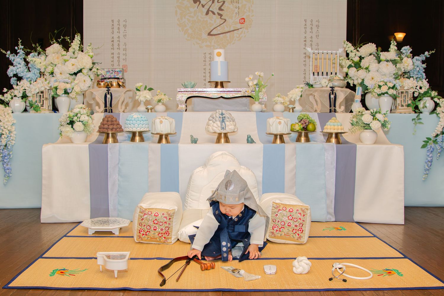 Baby photography set with white florals, soft blue stripes, and decorative elements arranged in a studio.