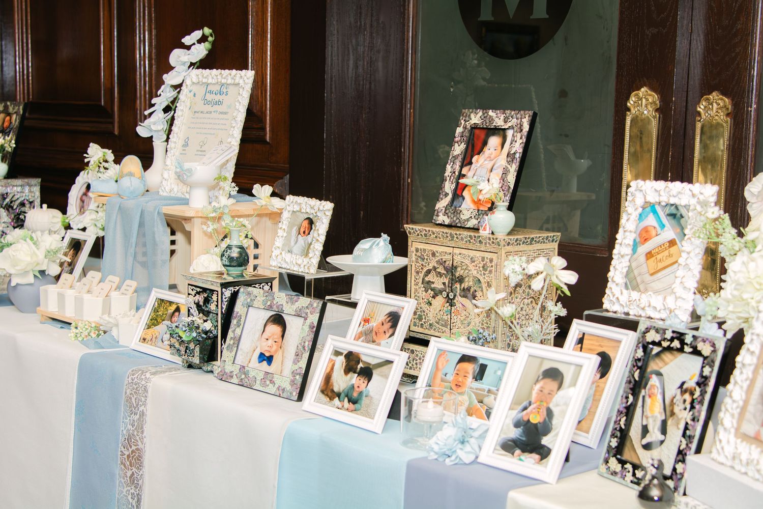 Display table decorated with floral arrangements and photo frames in blue and white theme.