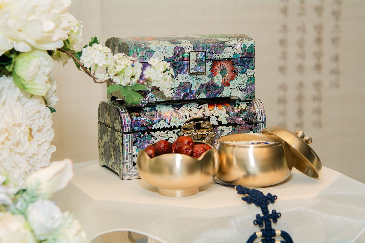 Elegant wedding reception table decor featuring delicate white flowers, soft lighting, and ornate Asian-inspired details.