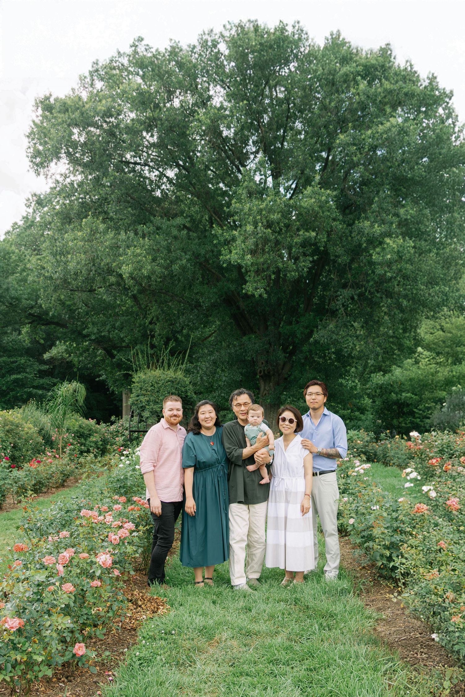 A group portrait taken outdoors in a lush garden with blooming roses.
