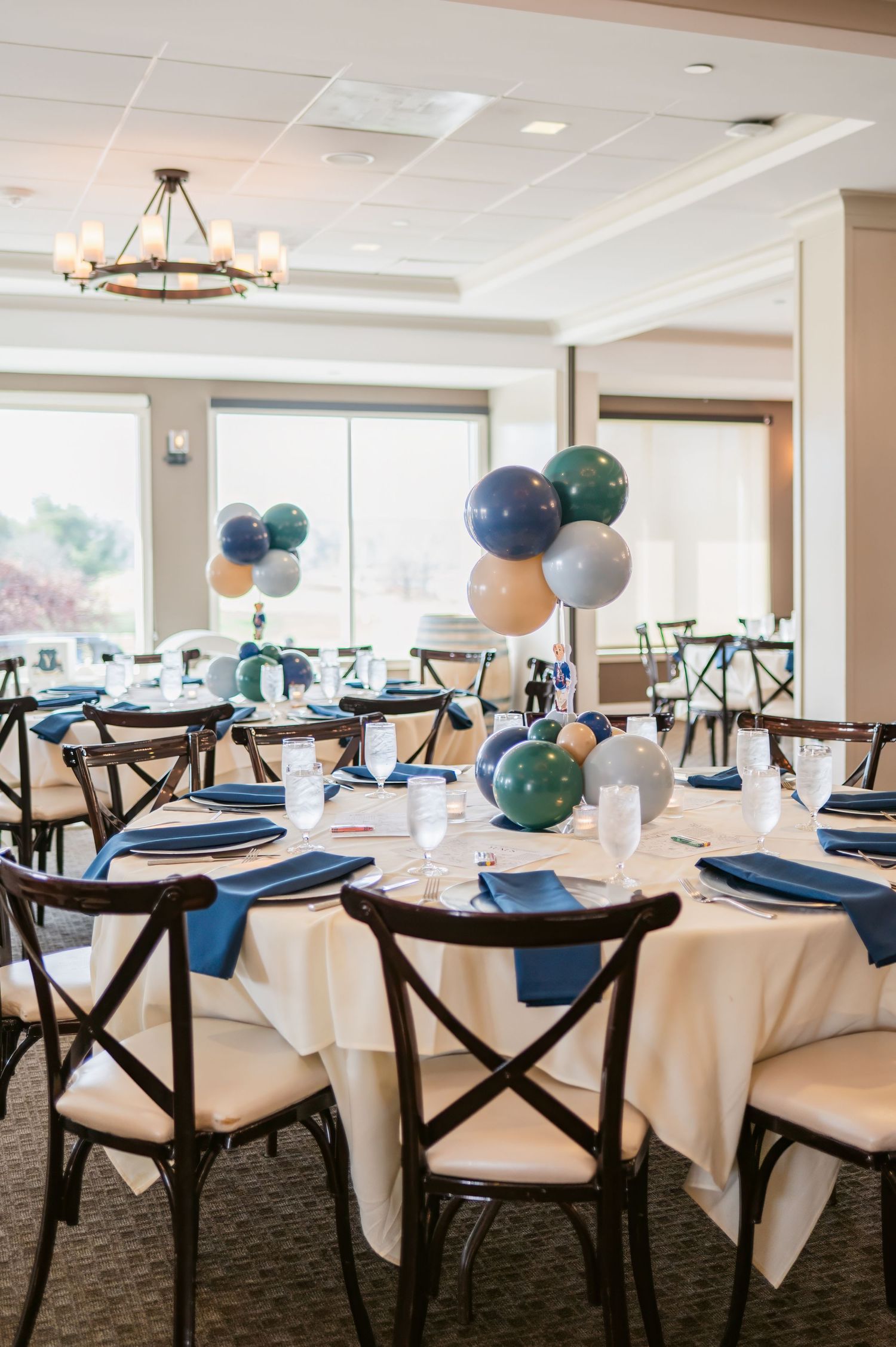 Elegant banquet hall setup with round tables decorated in navy blue and white with balloon centerpieces.
