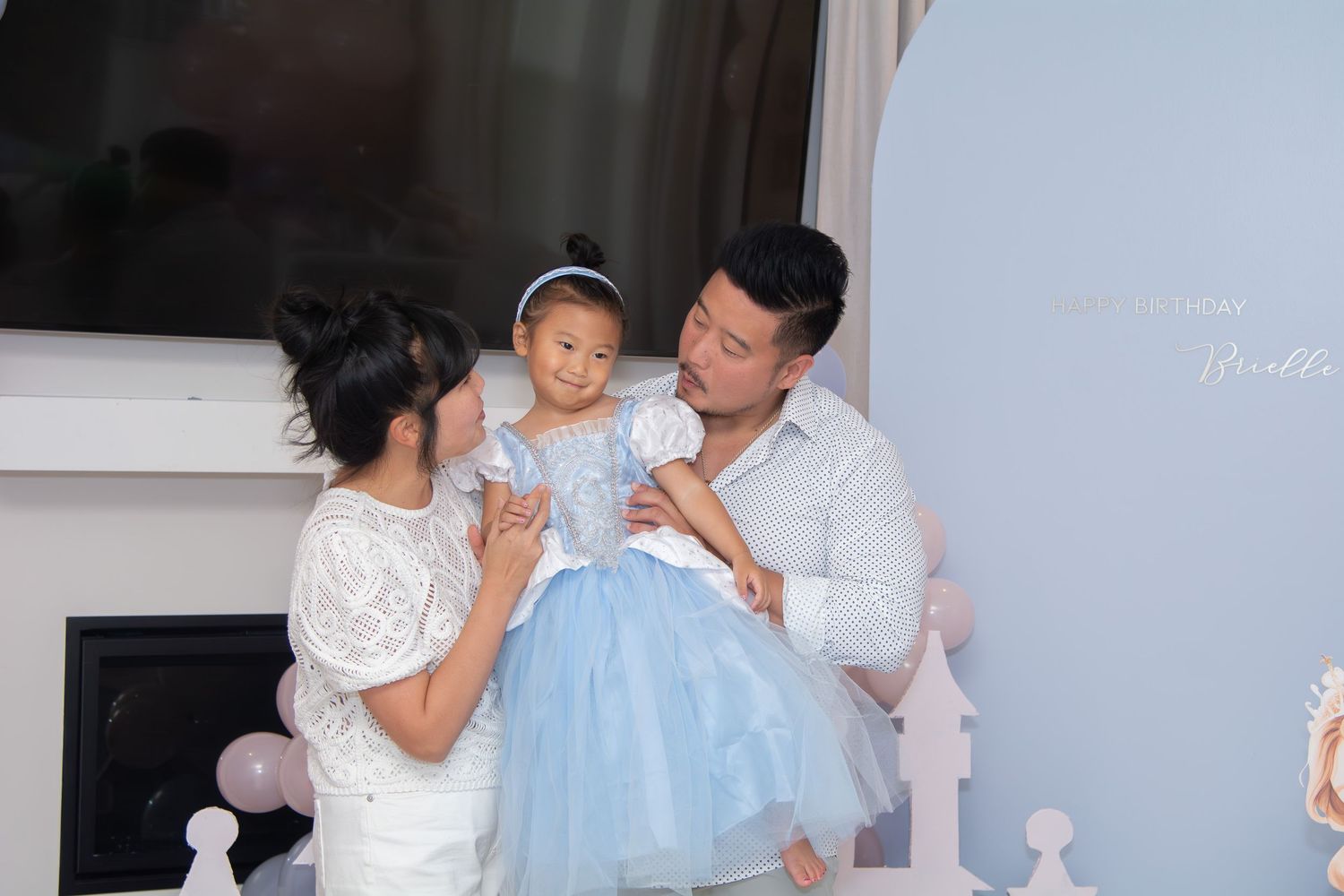 A series of four photos showing parents holding and playing with their baby in white and blue outfits.