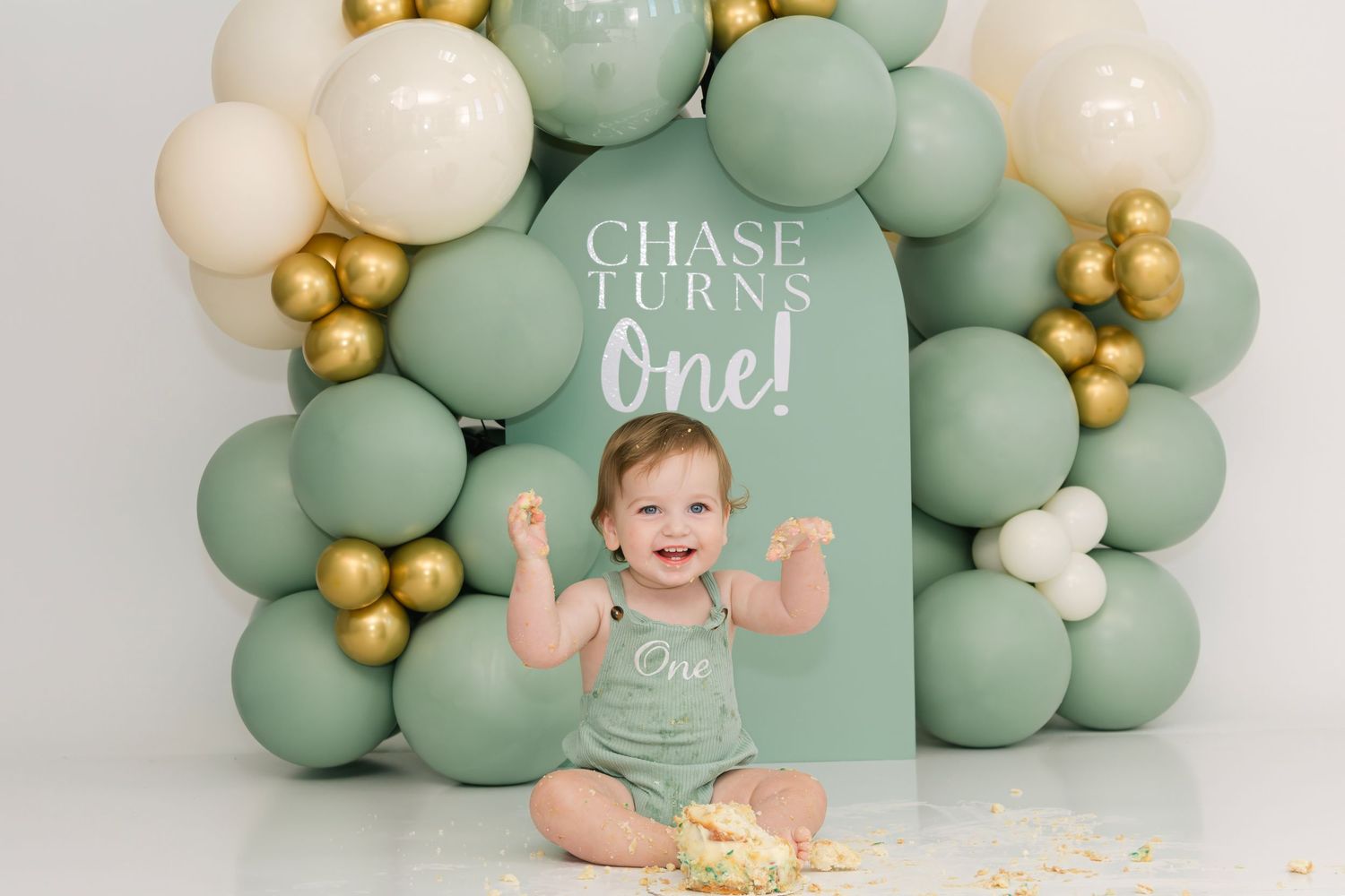 Cake smash photography setup with mint green and gold balloon arch.