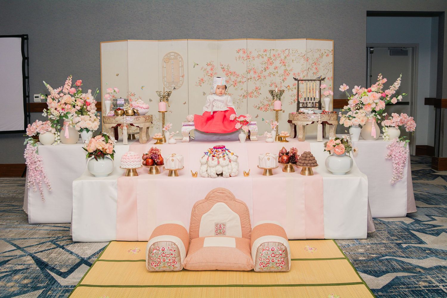 Pink and white party setup with floral arrangements and elegant table decorations.