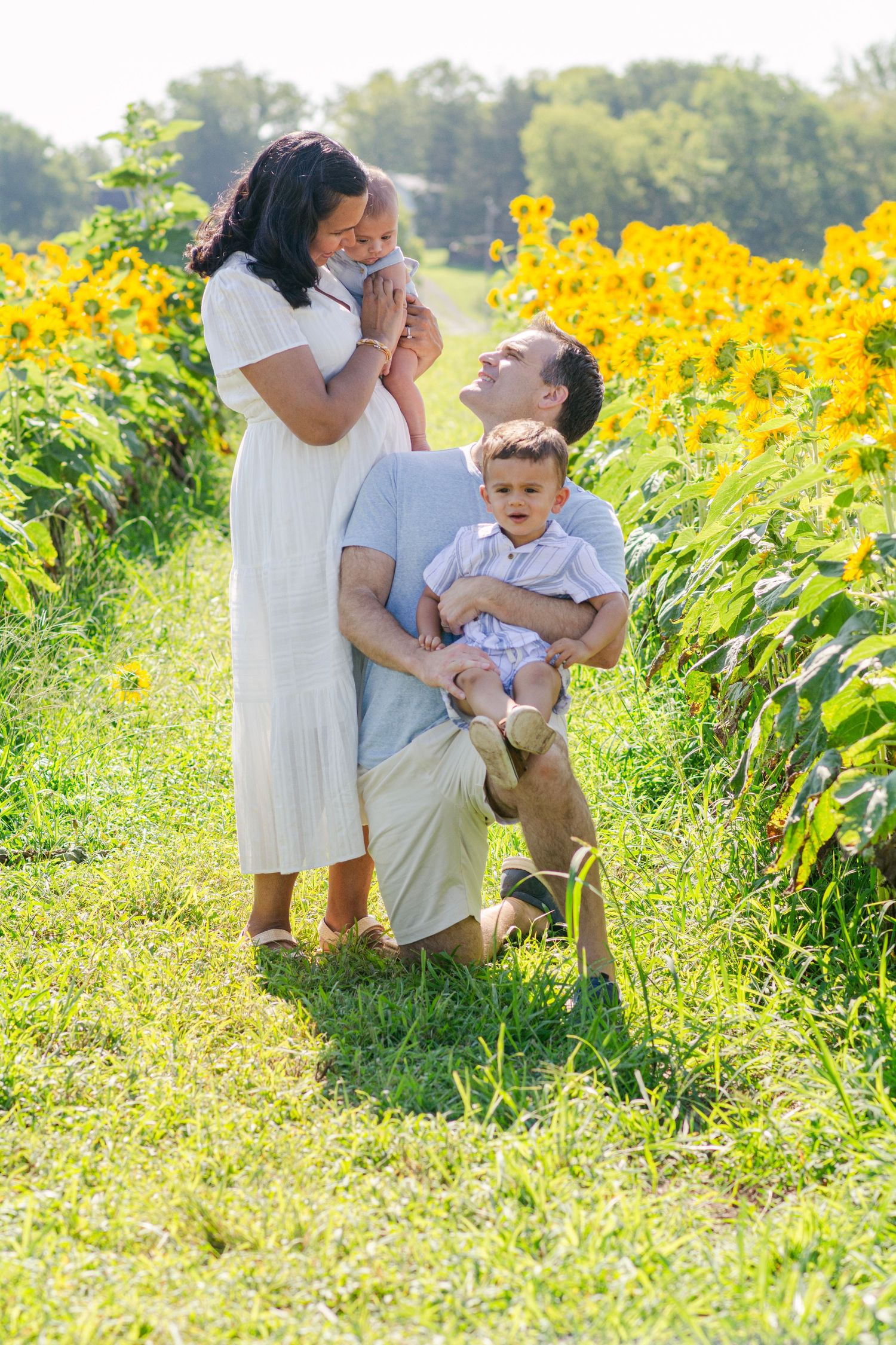 Family sharing joyful moments together among tall sunflowers in a summer field.