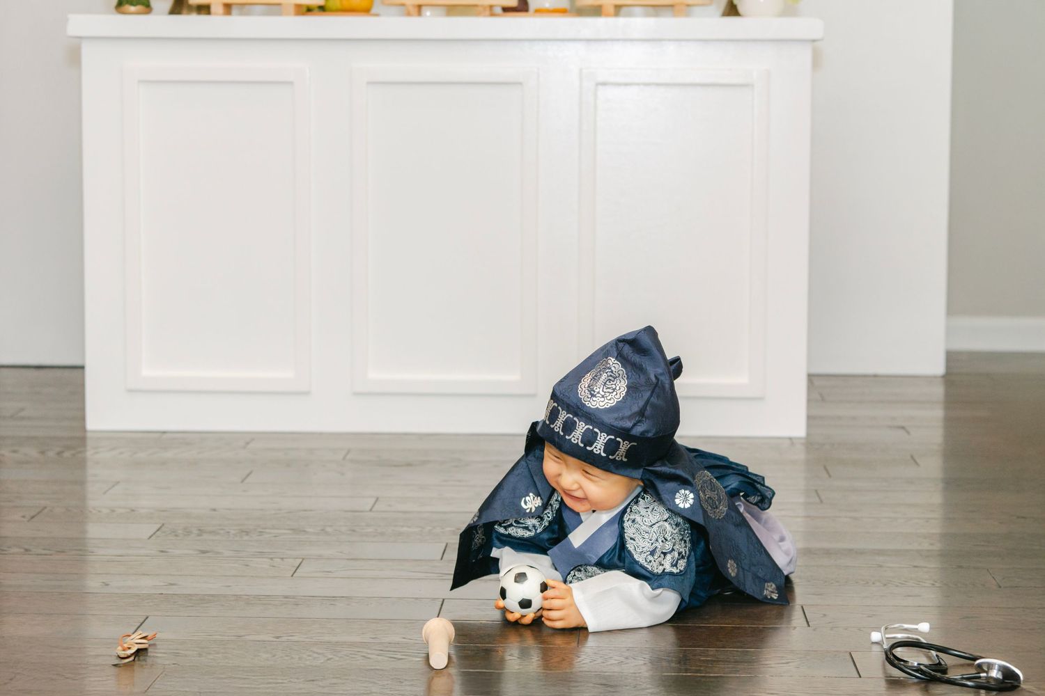 Child playing on floor near white furniture decorated with flowers and party accessories.