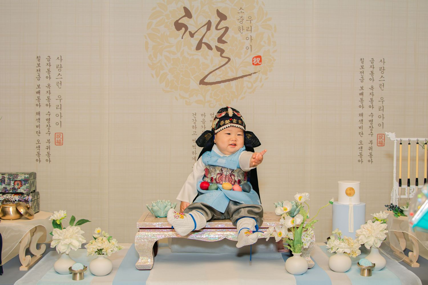 Decorative setup for a Korean dol party with pastel blue accents and white floral arrangements.