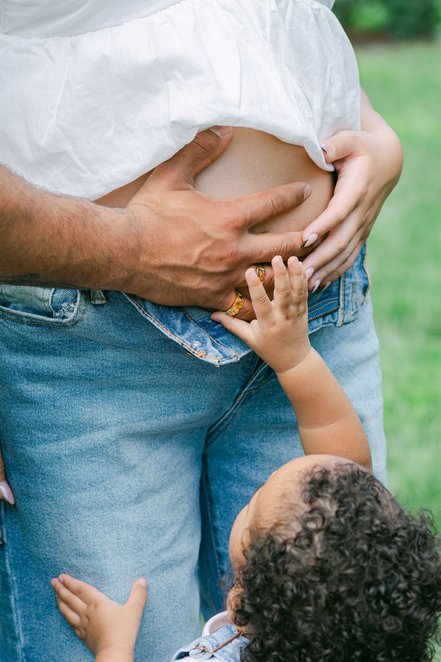 Candid outdoor family moment captured in natural light showing jeans and white clothing.
