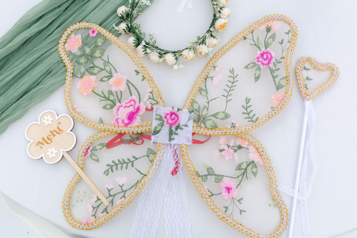 Delicate floral butterfly-shaped cookies with mint green icing and pink rose details on white background.