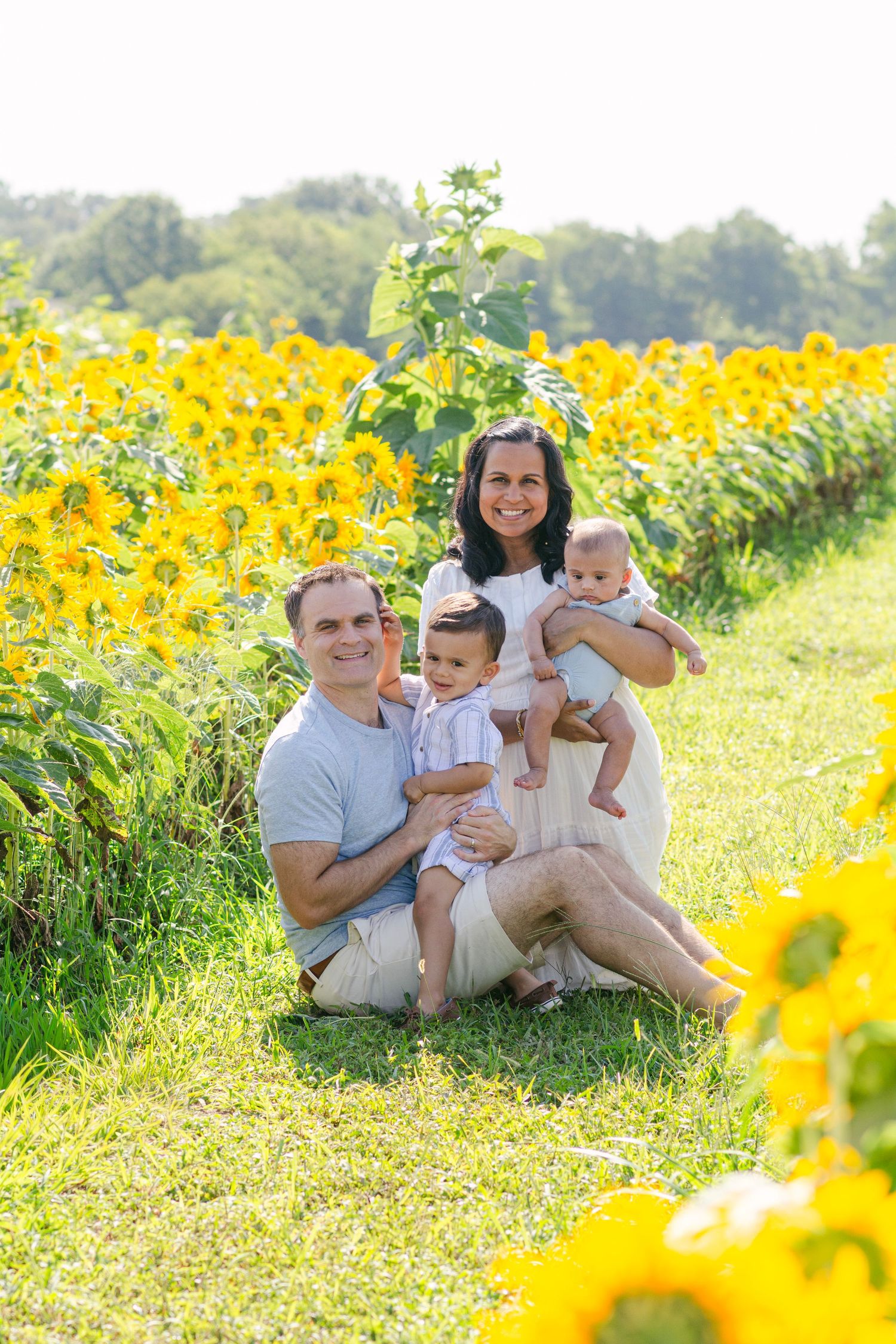 Happy family relaxing together in a bright sunflower field on a summer day.