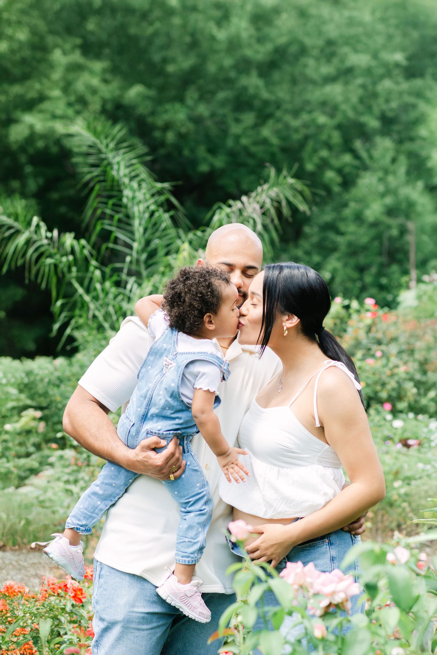 Family embracing in a garden setting surrounded by blooming flowers and greenery.