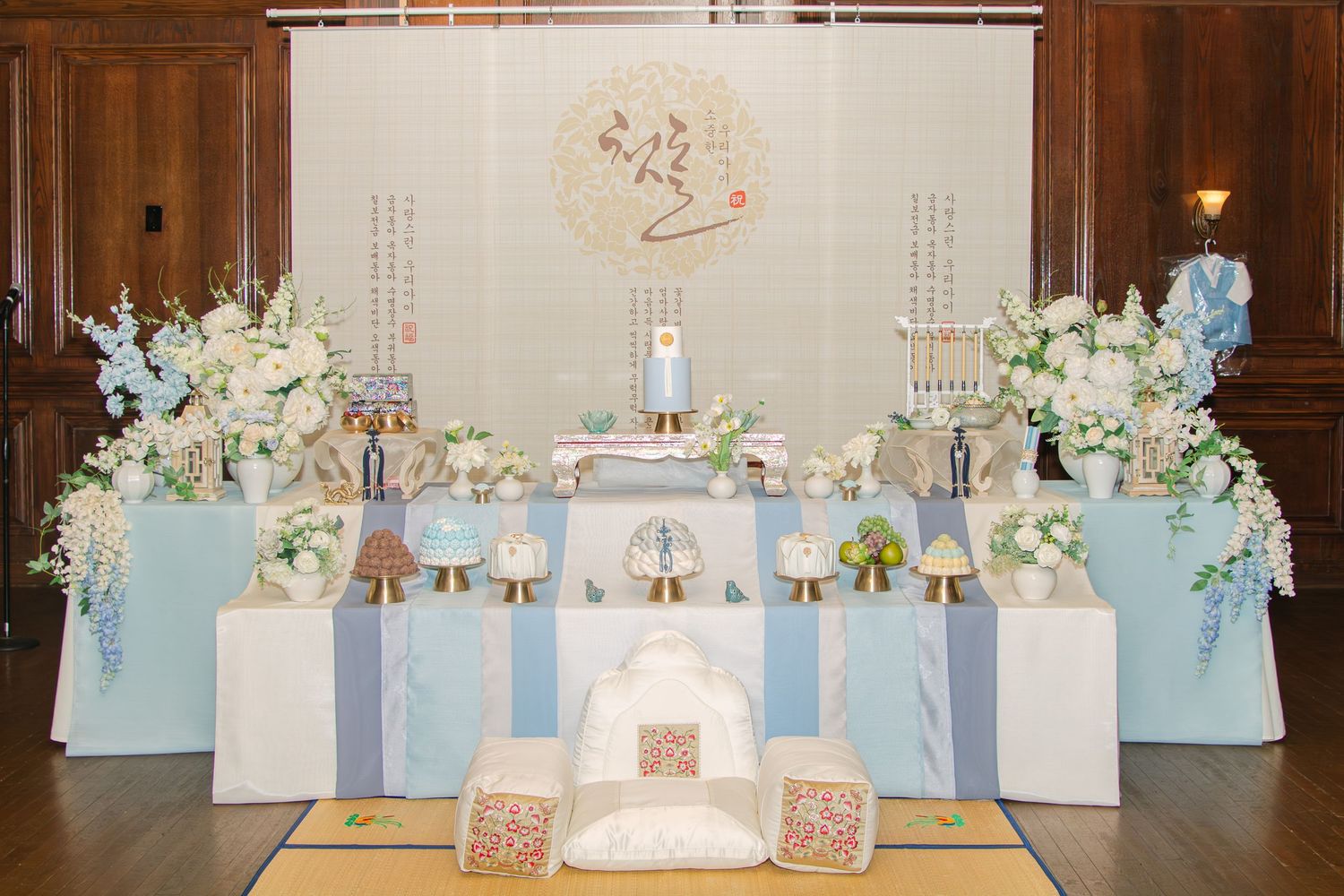 Elegant party setup with soft blue and white decor featuring floral arrangements and display panels in a formal room.