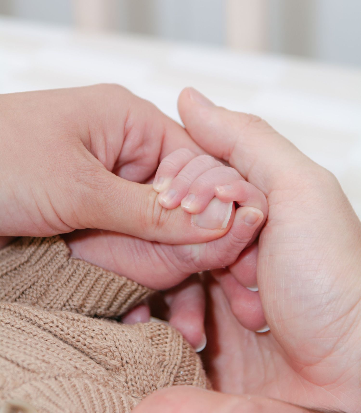 Close-up series of baby hands grasping fingers against a knit fabric background.