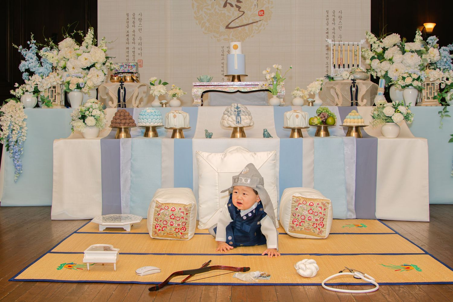Elegant event space decorated with white furniture, floral arrangements, and a light blue circular motif.
