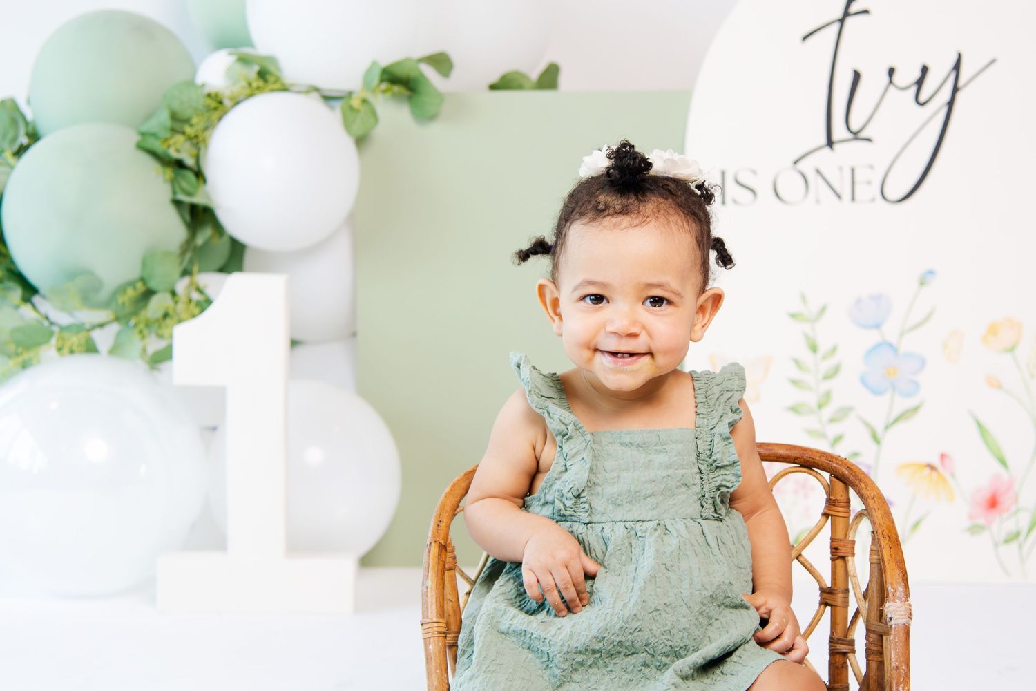 Festive first birthday setup with mint green balloons and floral decorations.