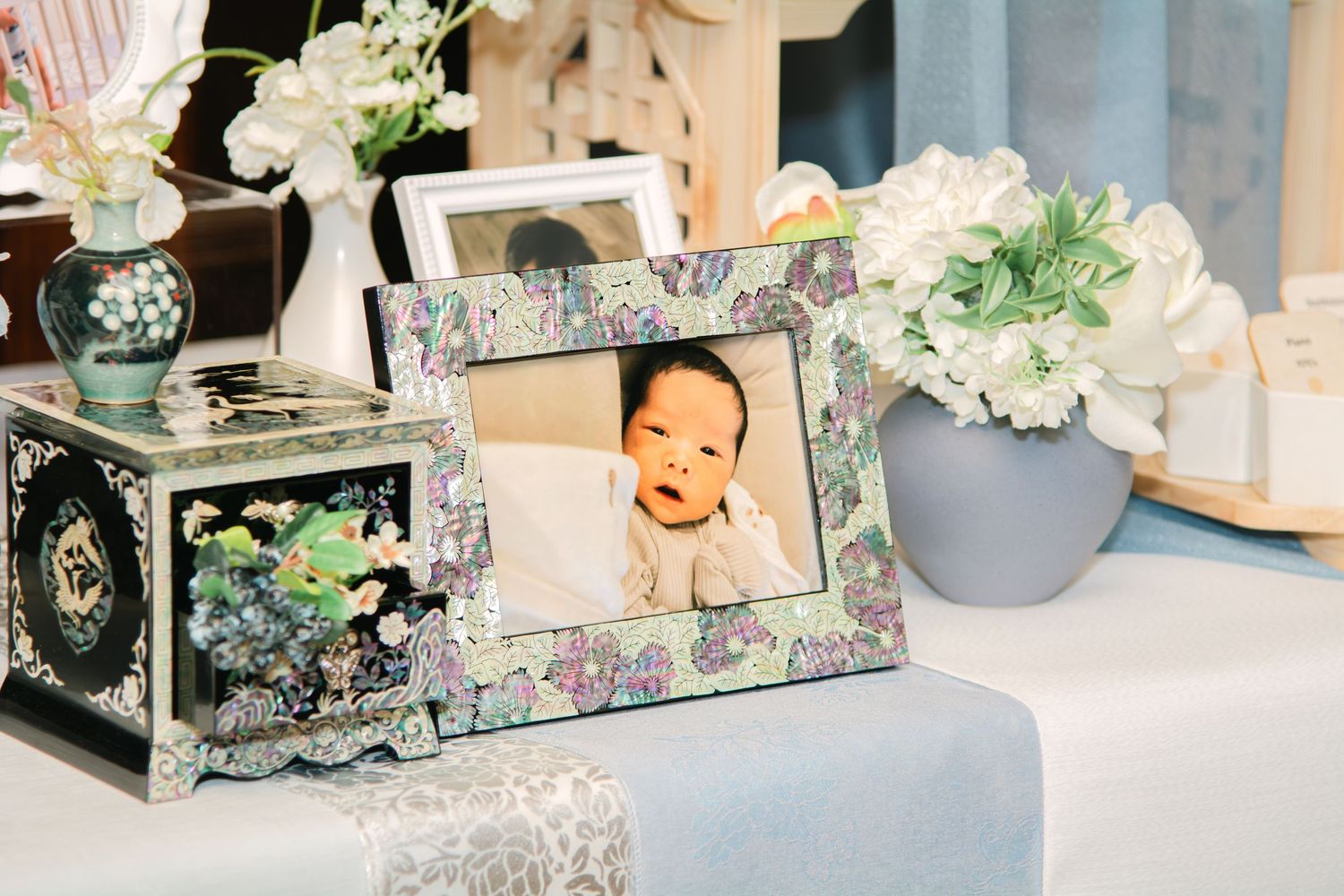 Decorative table setting with vintage style boxes and white floral arrangements in soft blue tones.