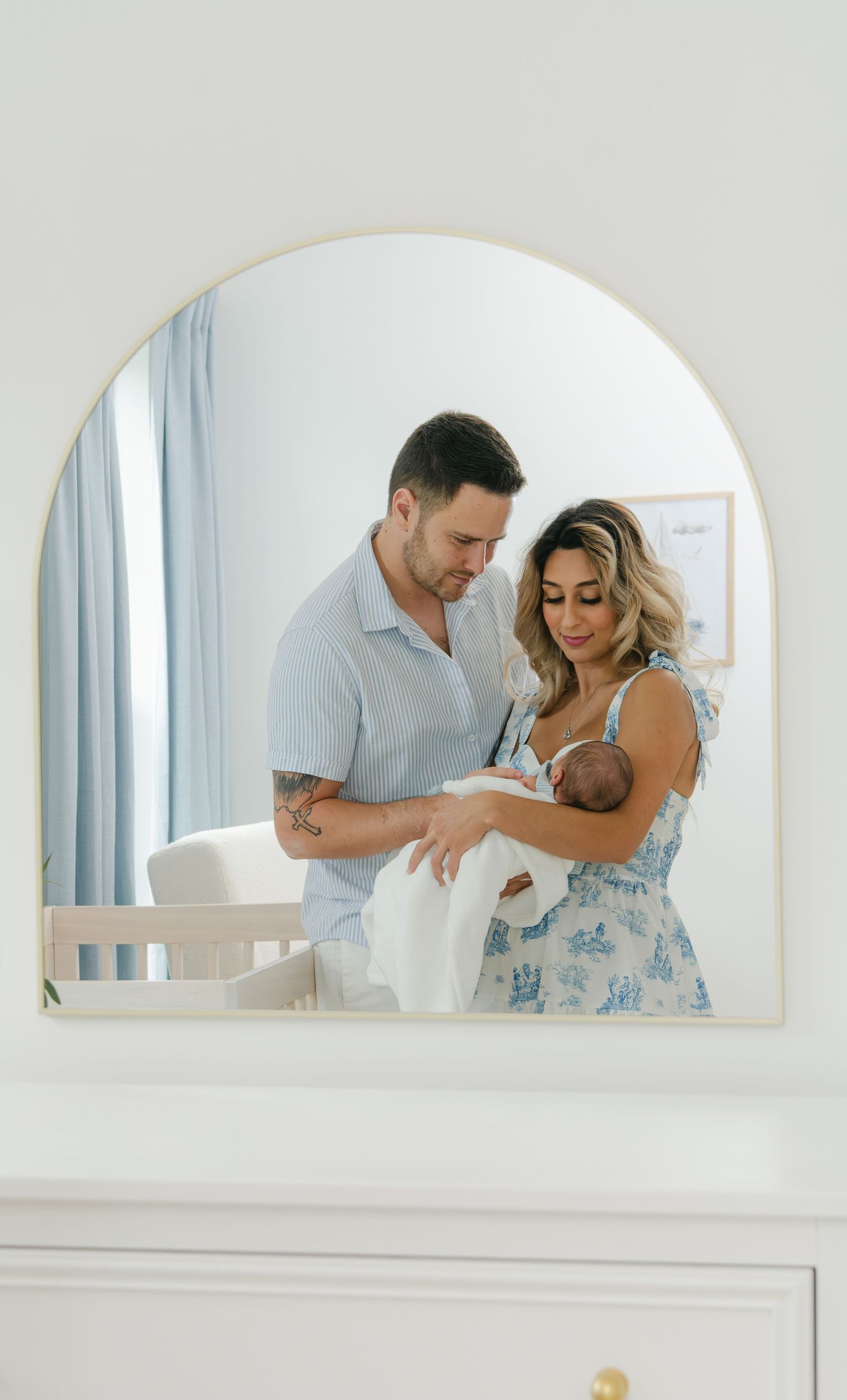 Couple shares intimate moment reflected in arched mirror.