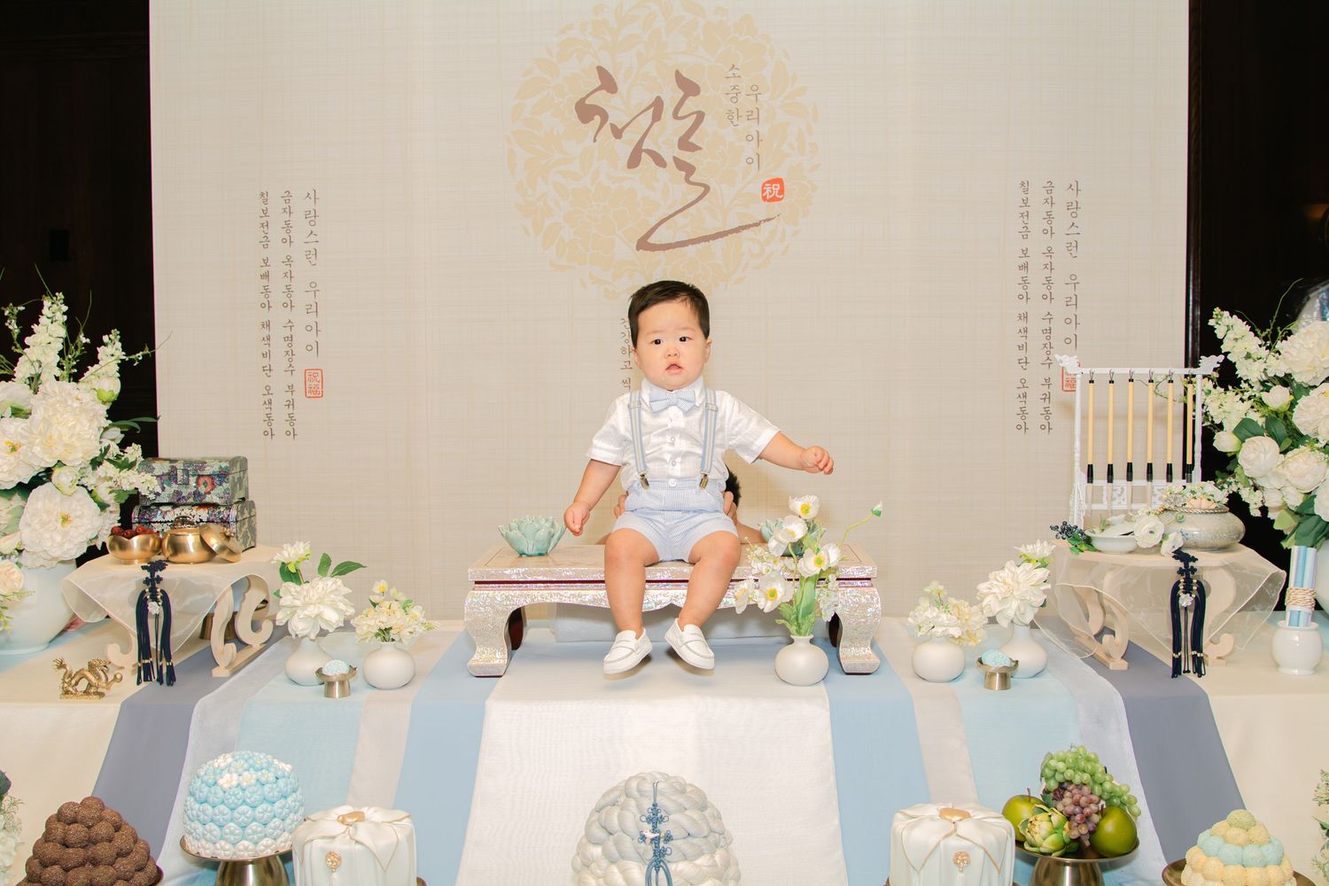 Traditional Korean-style celebration setup with decorative panels and floral arrangements.