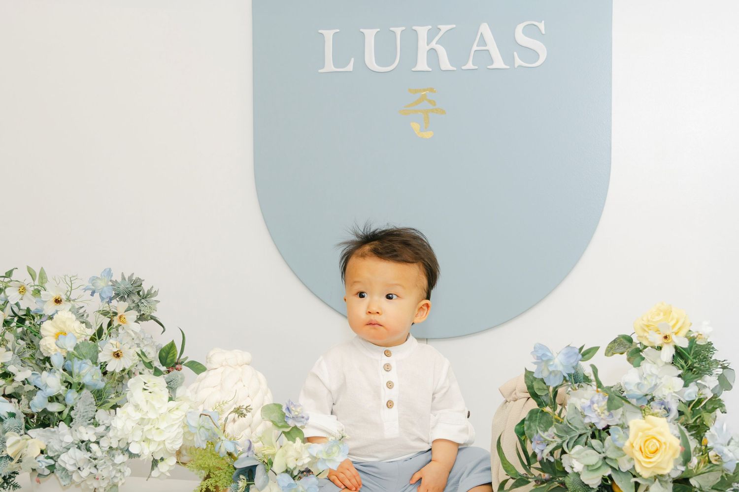 Elegant birthday setup with white and blue theme featuring floral decor and toys.