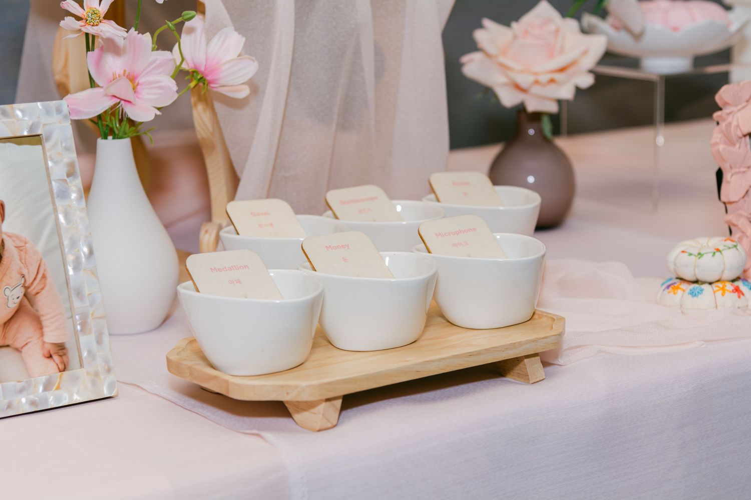 White ceramic cups arranged on a wooden serving tray with pink floral decorations.
