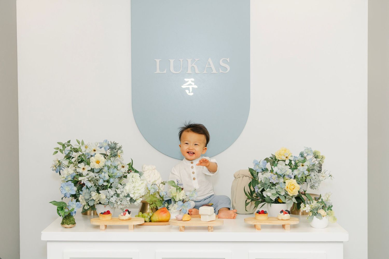Clean minimalist party setup with white furniture and pastel blue circular wall design.