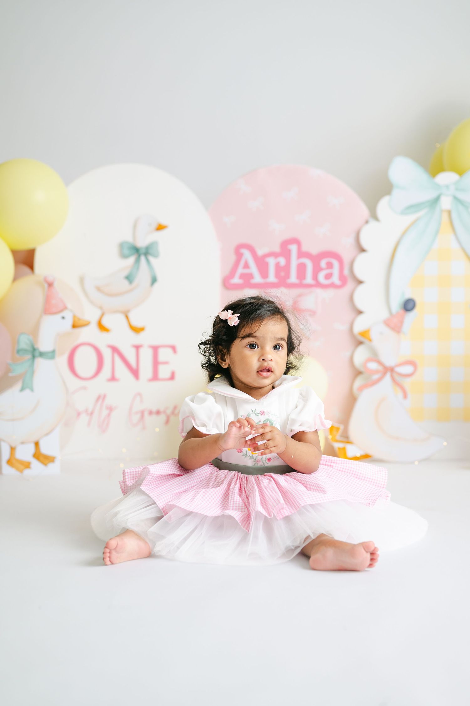 Baby girl Arha in pink tutu dress sits at her ONE birthday cake smash photo shoot with duck theme decor.