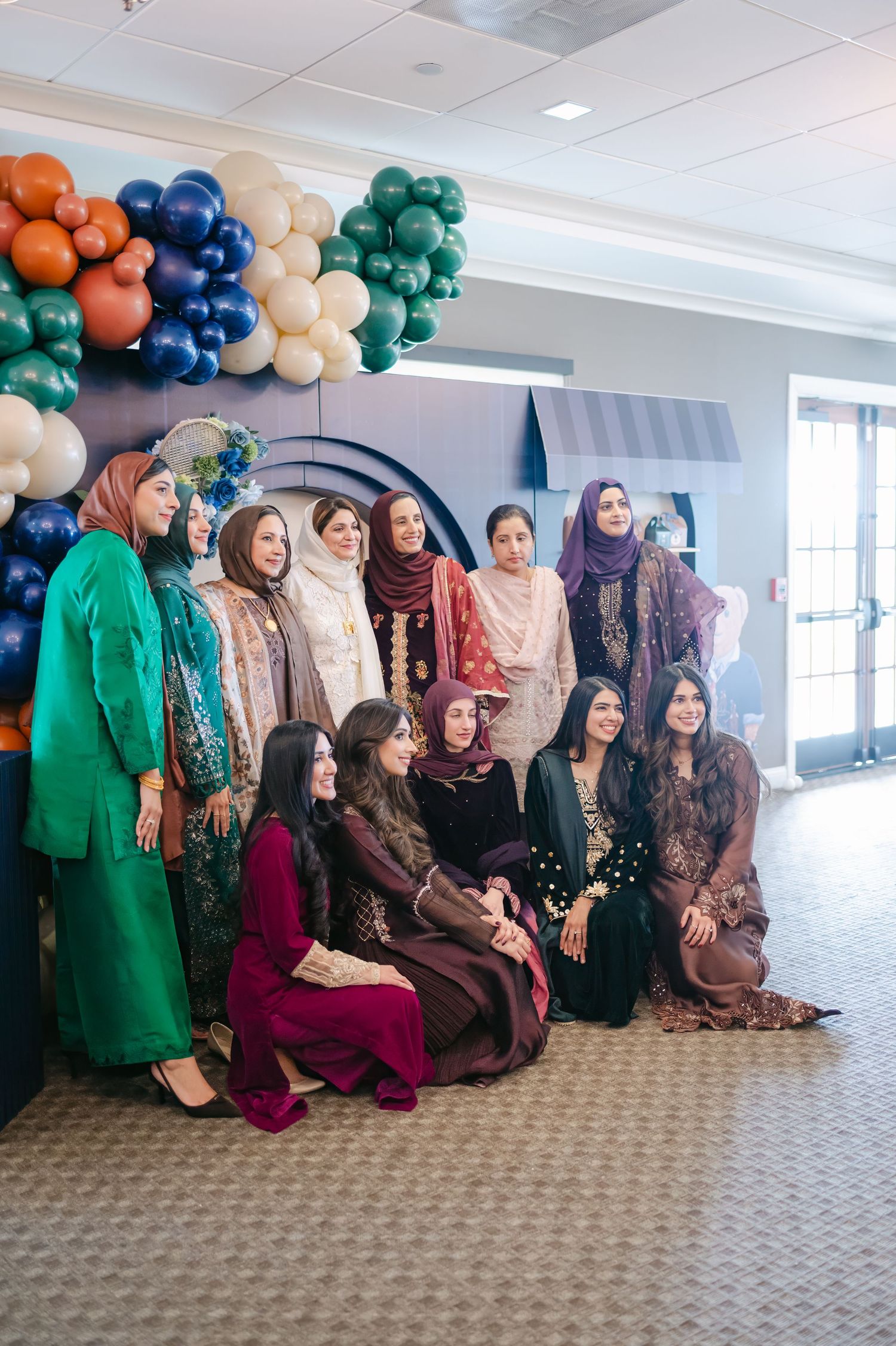 Group photo at an event with colorful balloon decorations and elegant traditional attire.