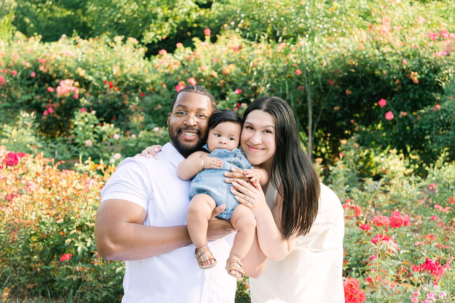 Family enjoying tender moments together in a garden with blooming roses.