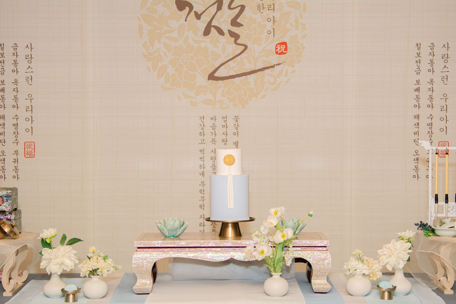 Asian-inspired wall art backdrop with elegant party decor and white floral arrangements.