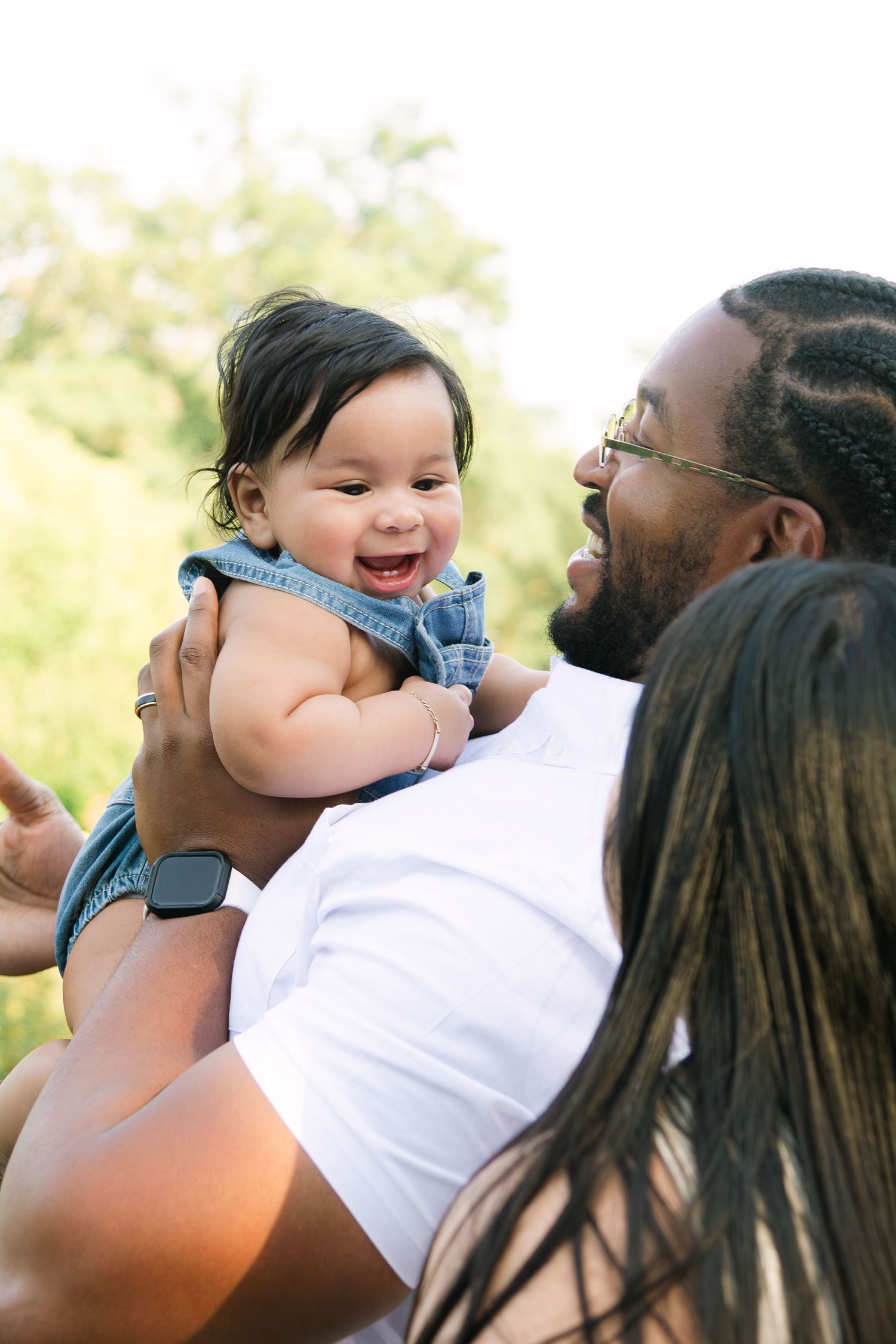 Family sharing playful moments and laughter in bright outdoor lighting.