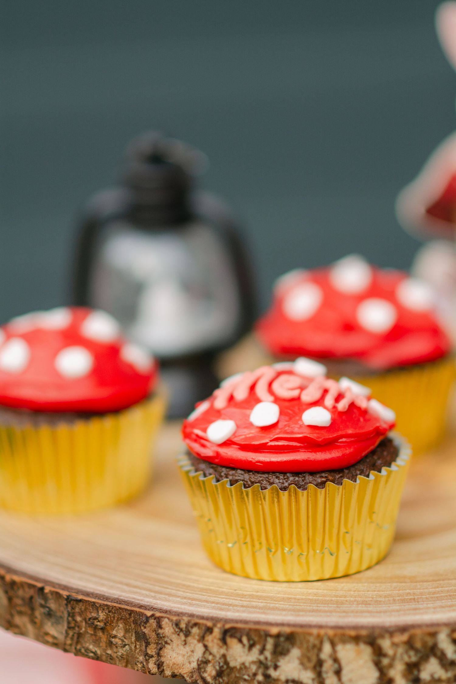 Red and yellow frosted cupcakes arranged on a rustic wooden serving board with shallow depth of field.